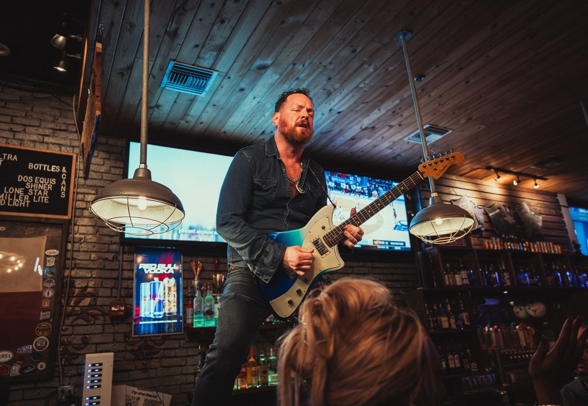 Dave Menzo playing guitar at a bar show